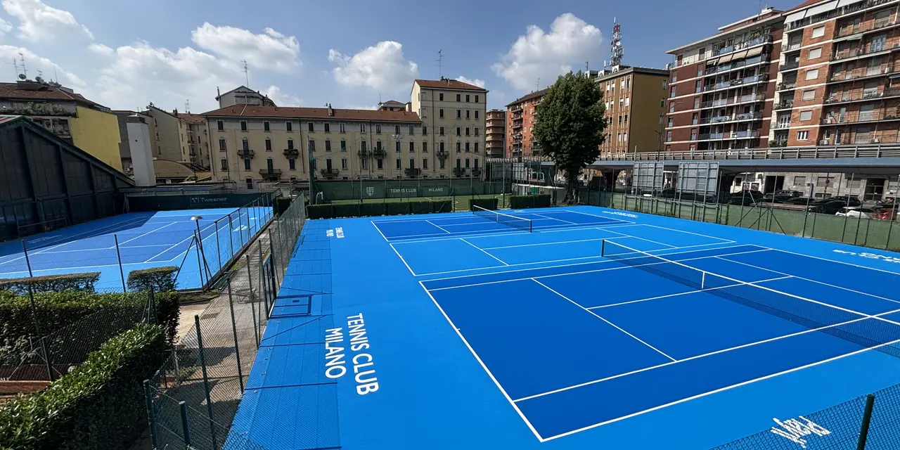 Campi da tennis blu in un complesso urbano, circondati da edifici residenziali.