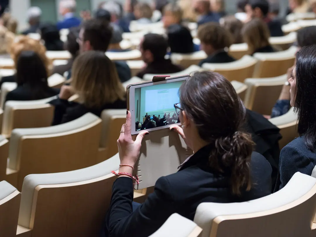 Platea in auditorium con pubblico e dispositivo tablet