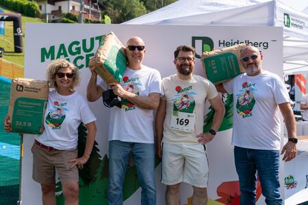 Gruppo di persone in posa davanti a uno stand Heidelberg Materials con sacchi di cemento.