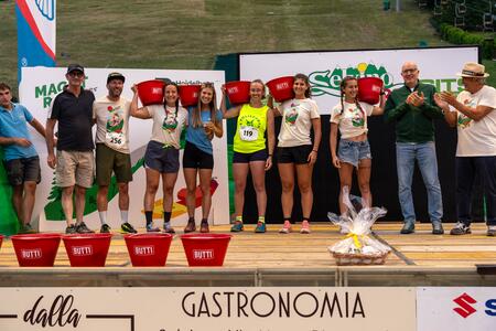 Un gruppo di persone premiate su un palco, ciascuna con un secchio rosso e una maglietta con logo. 