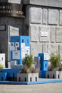 Installazione esterna con blocchi in cemento e piante, posizionata davanti a un edificio in pietra.